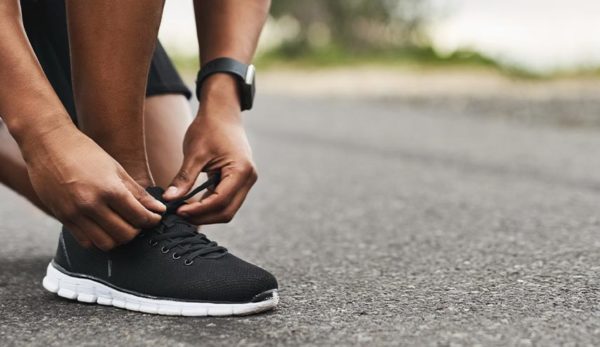 Closeup shot of a person tying his shoelaces while exercising outdoors
