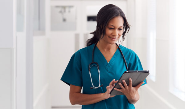 Female doctor wearing scrubs In hospital using tablet
